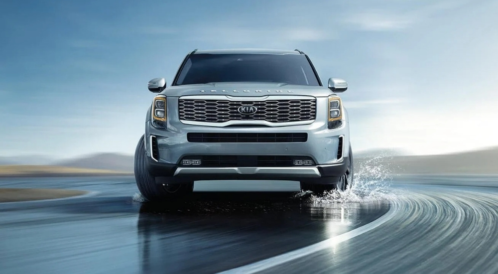 A silver 2021 Kia Telluride is shown driving to a used Kia dealer.
