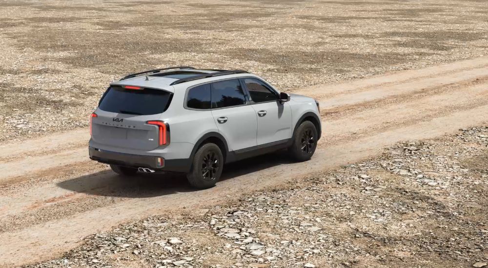 Rear overhead view of a grey 2025 Kia Telluride SX Prestige X-Pro driving on a dirt road.