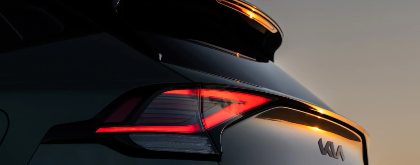 The brakelight on a black 2025 Kia Sportage during a sunset.