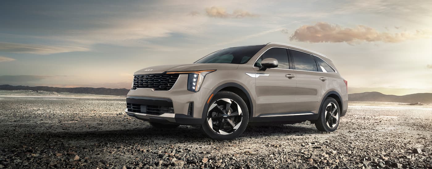 A tan 2025 Kia Sportage Plug-in Hybrid SX driving on gravel.