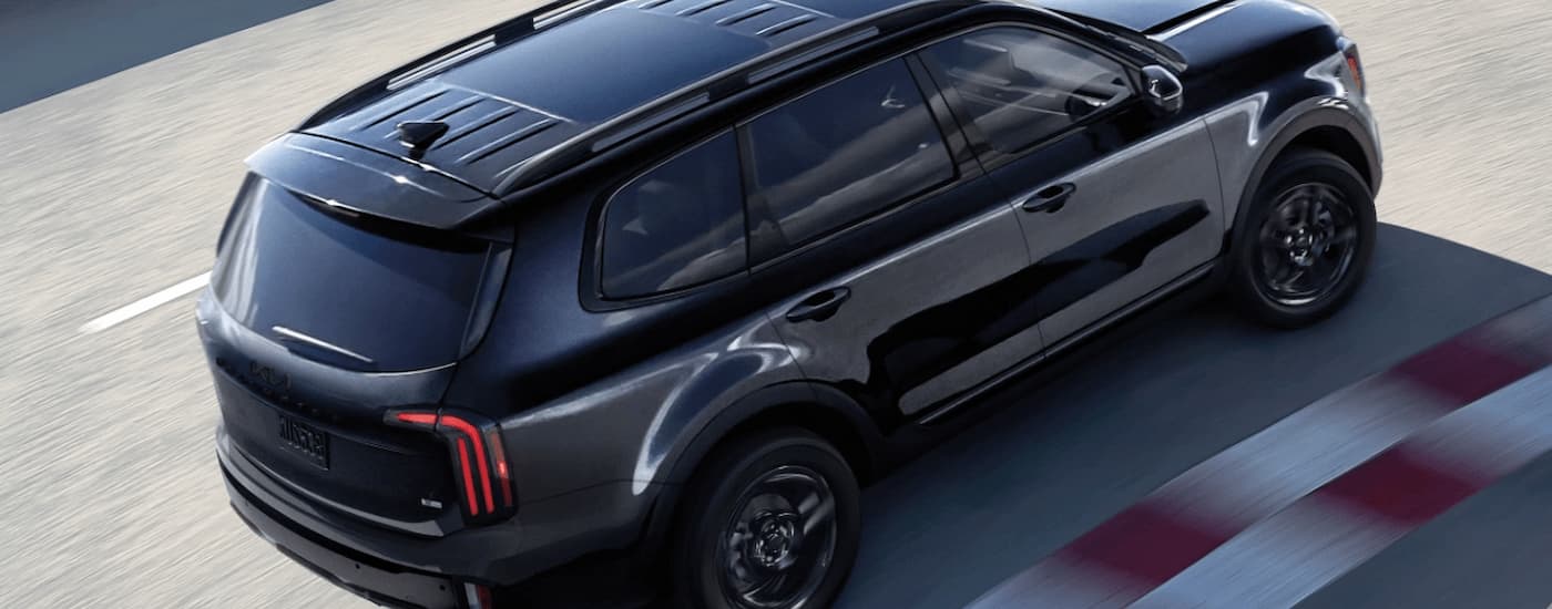 A black 2025 Kia Telluride is driving on a track.