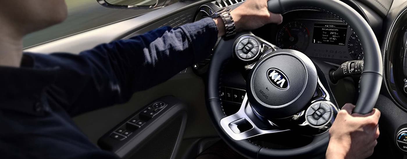 A close up of a man driving a 2020 Kia Soul during a test drive.